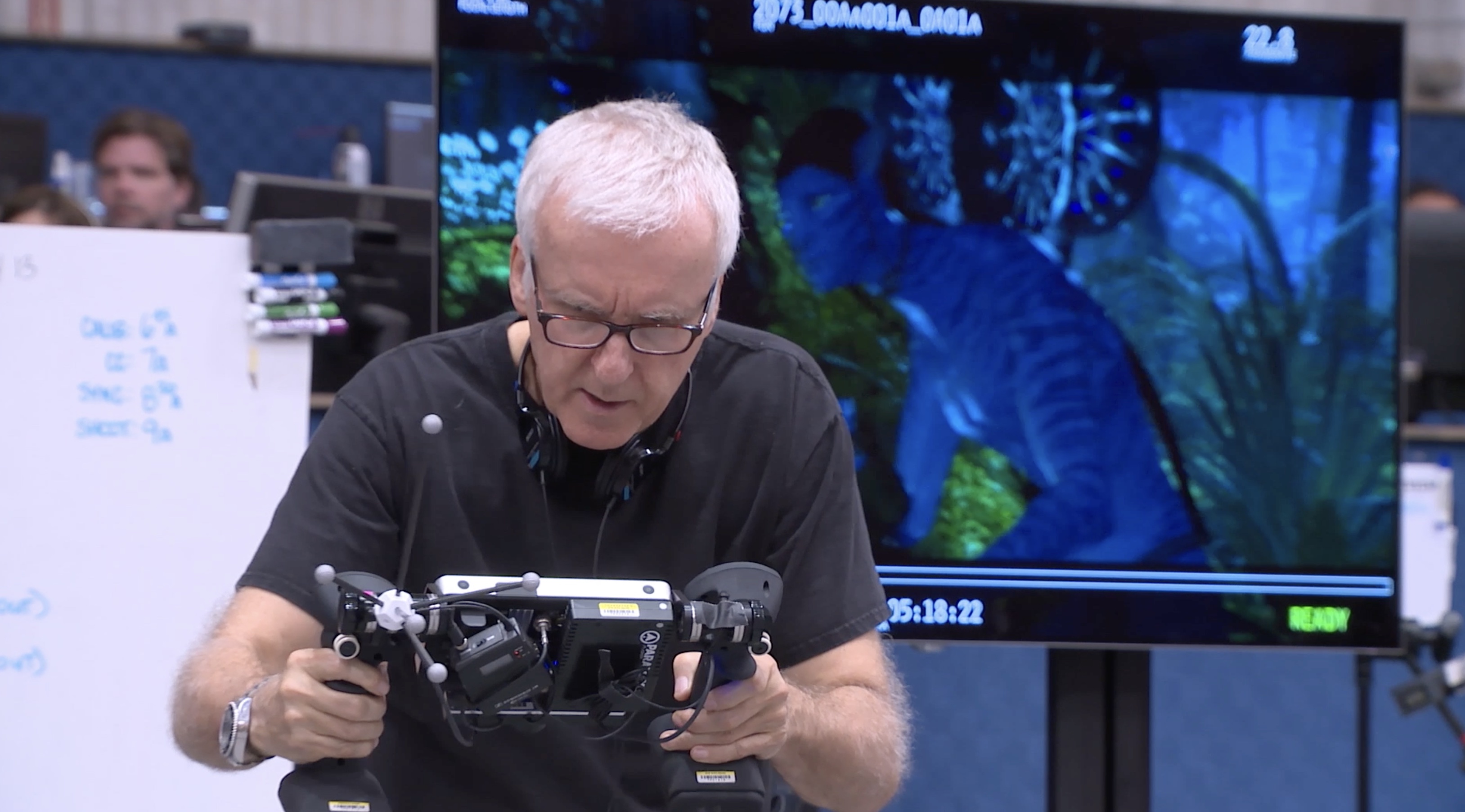 James Cameron squints down at a virtual camera screen while a bit of half-rendered Avatar footage plays in the background