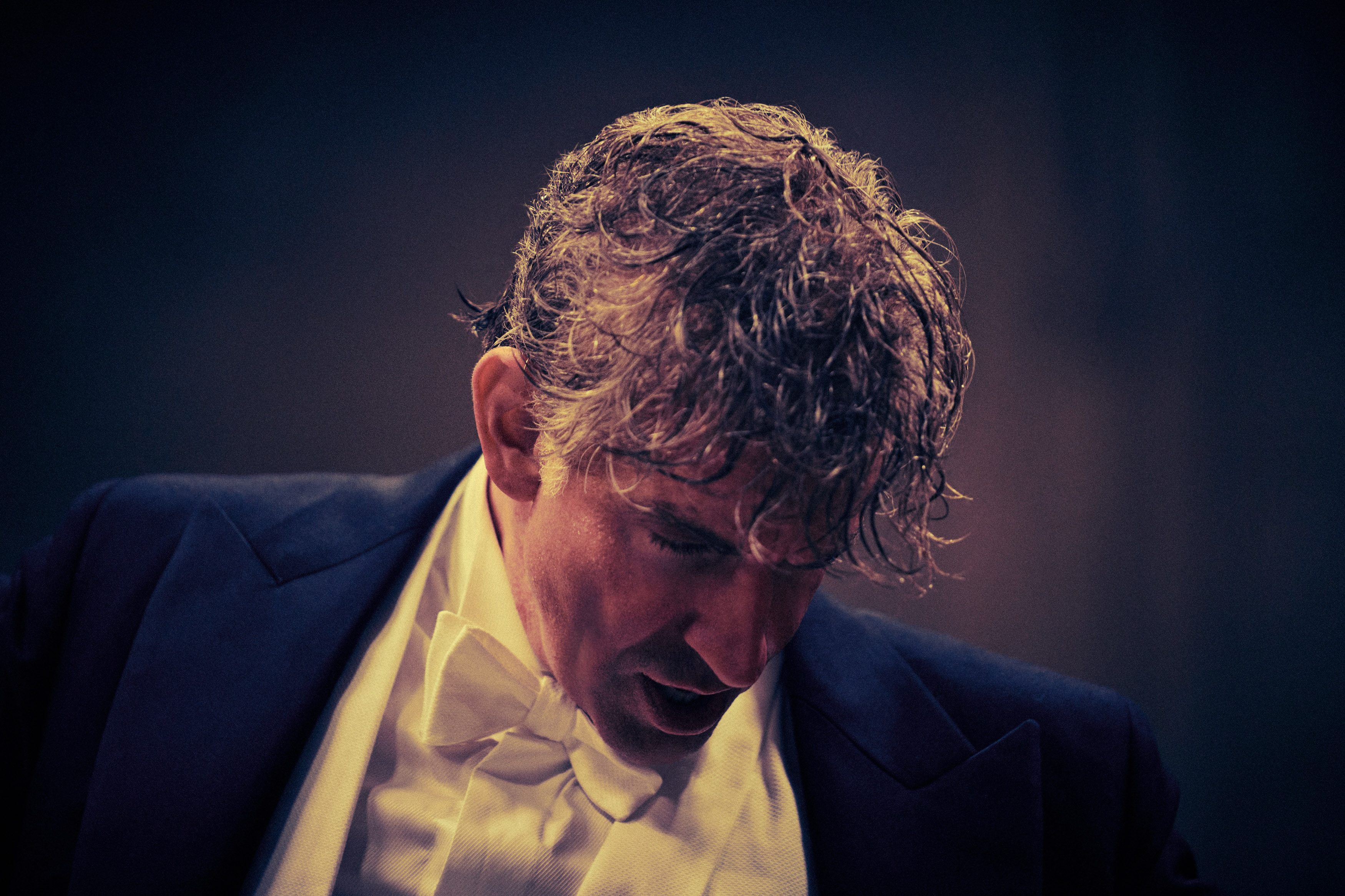 Bradley Cooper in closeup as a sweaty, tangle-haired Leonard Bernstein in Netflix’s Maestro